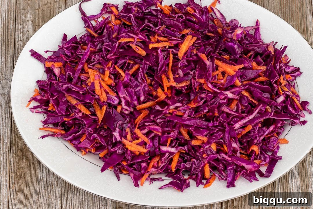 A close-up shot of a serving platter filled with colorful red cabbage slaw, highlighting the shredded texture and freshness of the vegetables.