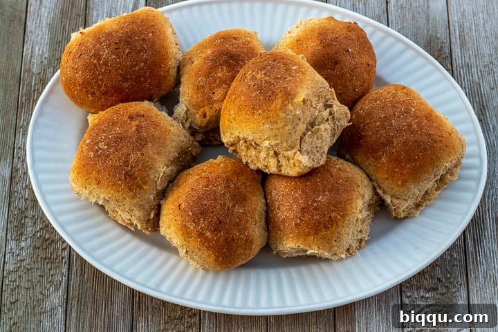Whole wheat rolls on a white serving platter.