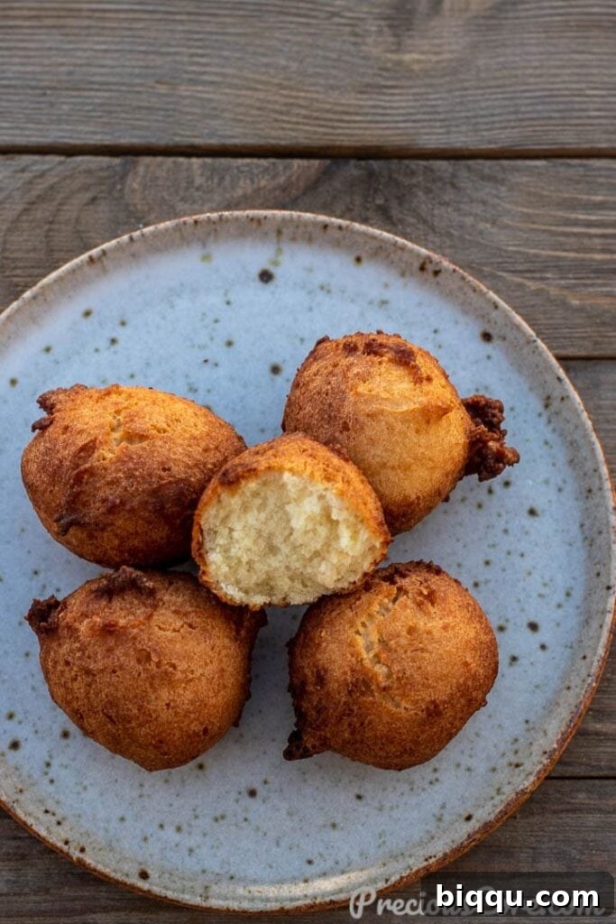 Fluffy Coconut Doughnuts 2 Golden brown coconut doughnuts on a plate with one opened up to show the soft interior