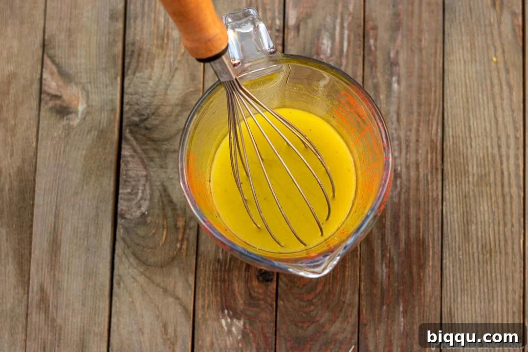 A simple yet elegant lemon vinaigrette in a clear measuring cup, showing the beautifully combined oil and lemon juice.