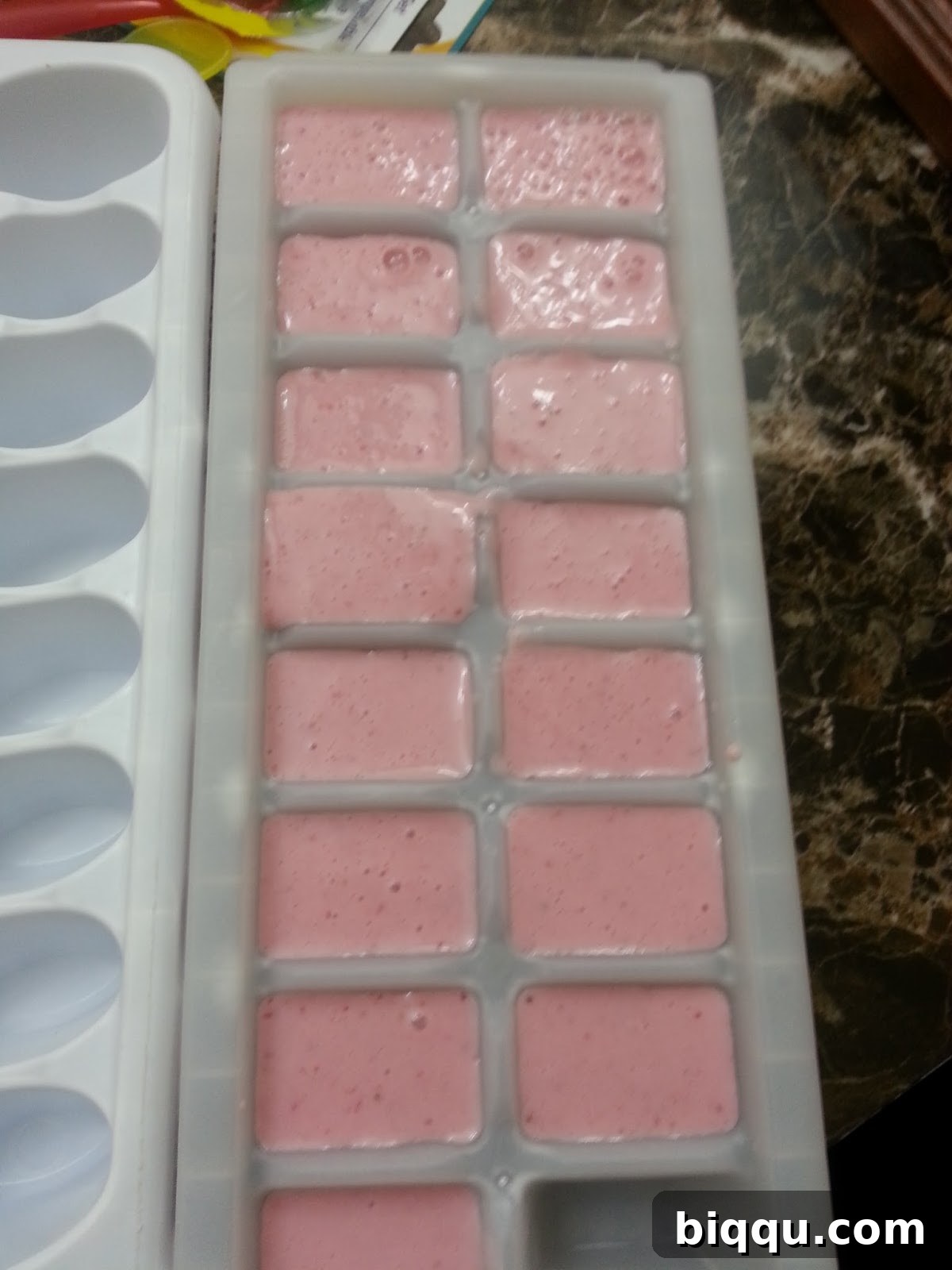 Strawberry yogurt mixture poured into ice cube trays