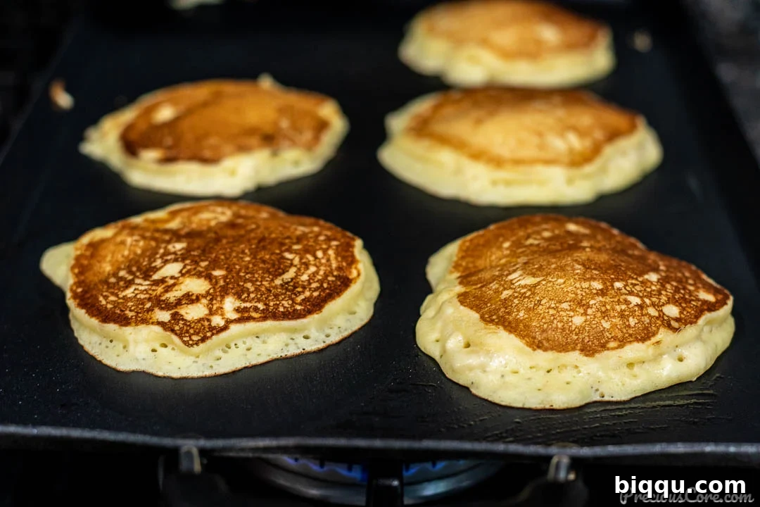 Banana Pancakes Cooking on Griddle, golden brown and ready to flip