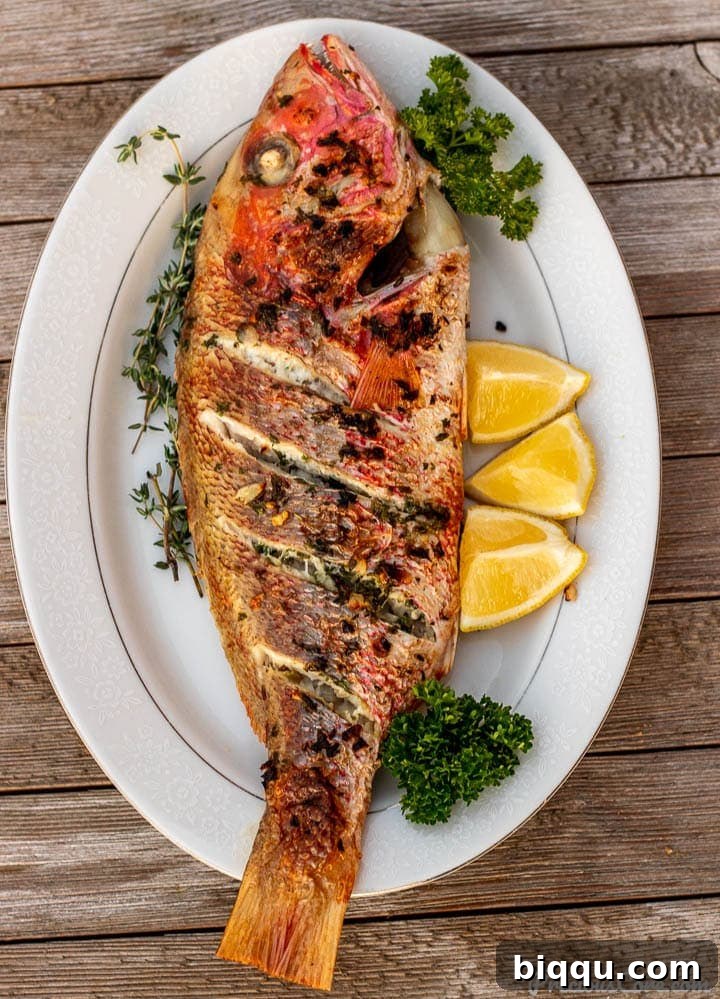 Golden Oven Grilled Whole Red Snapper 2 Perfectly oven-grilled whole red snapper served on a platter, garnished with fresh herbs and lemon slices
