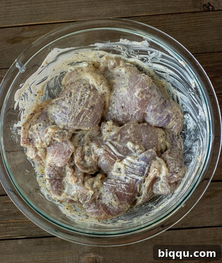 Succulent Grilled Boneless Chicken Thighs 4 Chicken thighs marinating in a creamy yogurt and spice mixture in a bowl