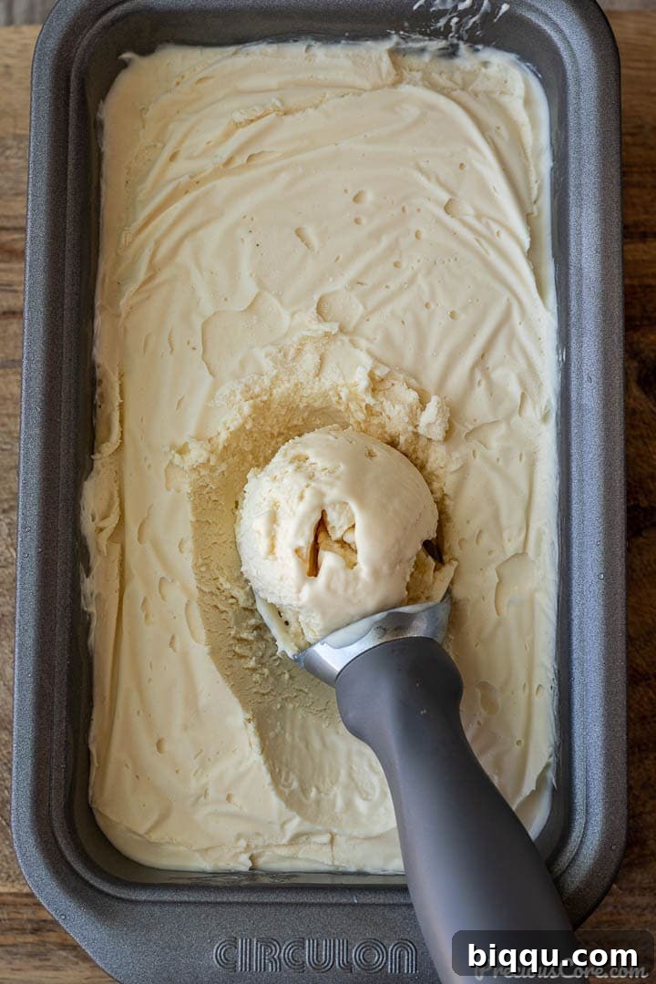 Homemade vanilla ice cream in a loaf pan with a scoop on top, ready to be served.