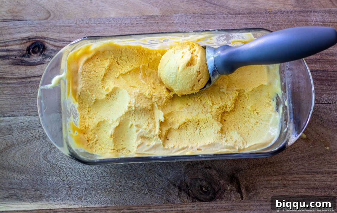 Homemade no-churn mango ice cream served in a loaf pan, ready for scooping.