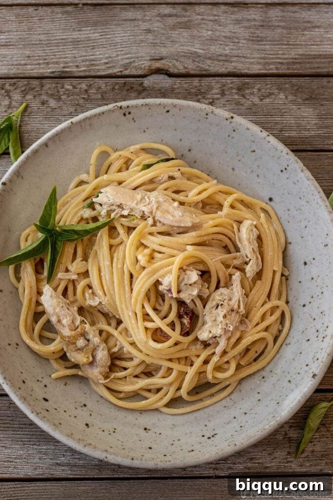 creamy chicken spaghetti in a bowl, garnished with fresh herbs