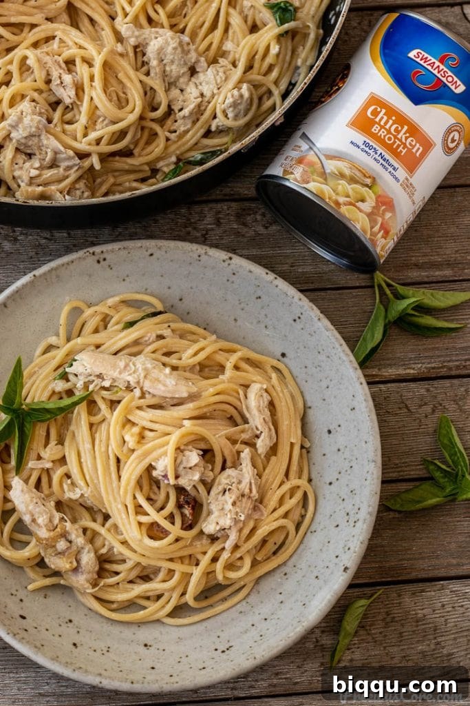 spaghetti and chicken in a bowl, can of chicken broth nearby, highlighting key ingredients