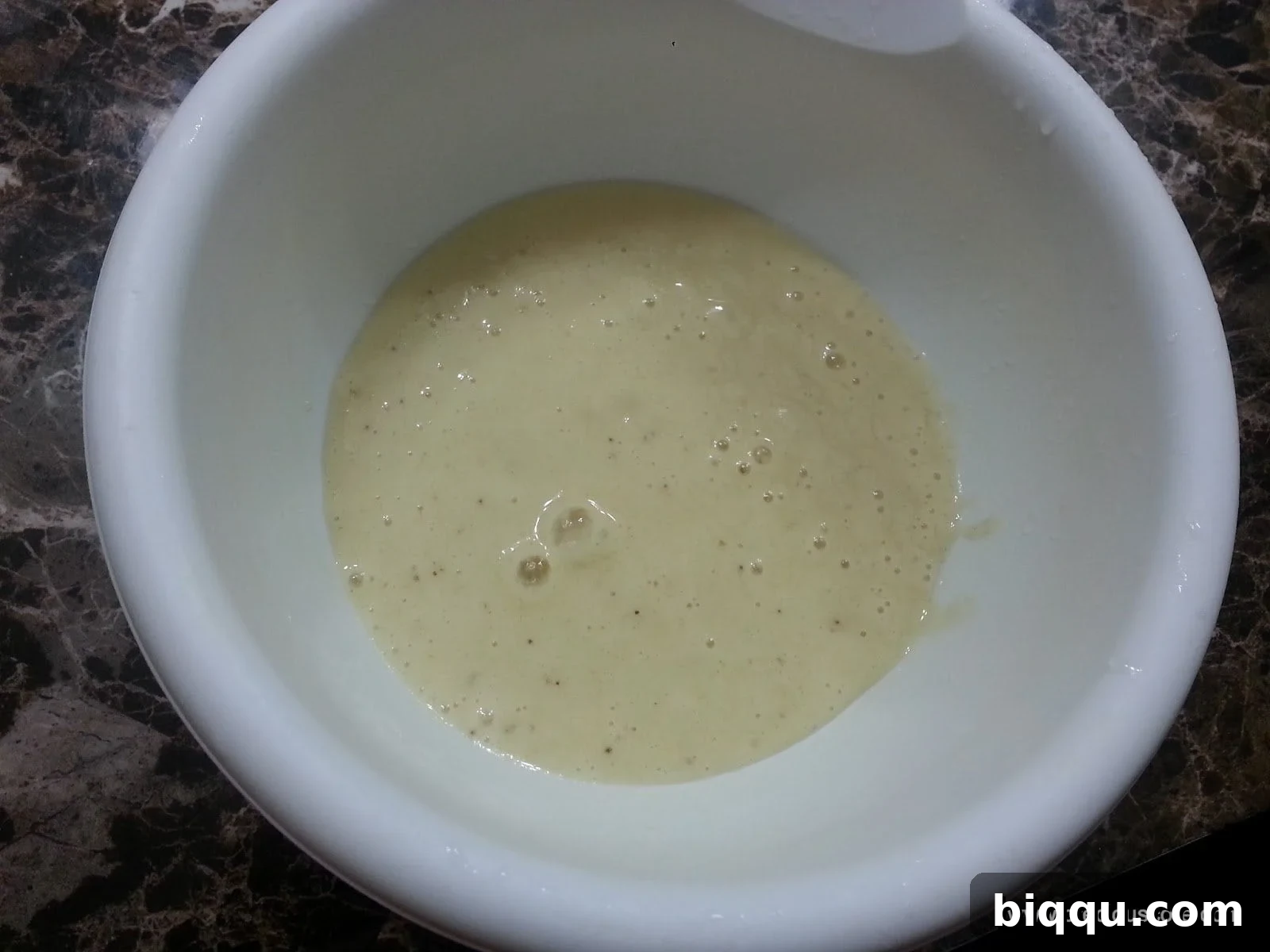 Banana and liquid in a mixing bowl.