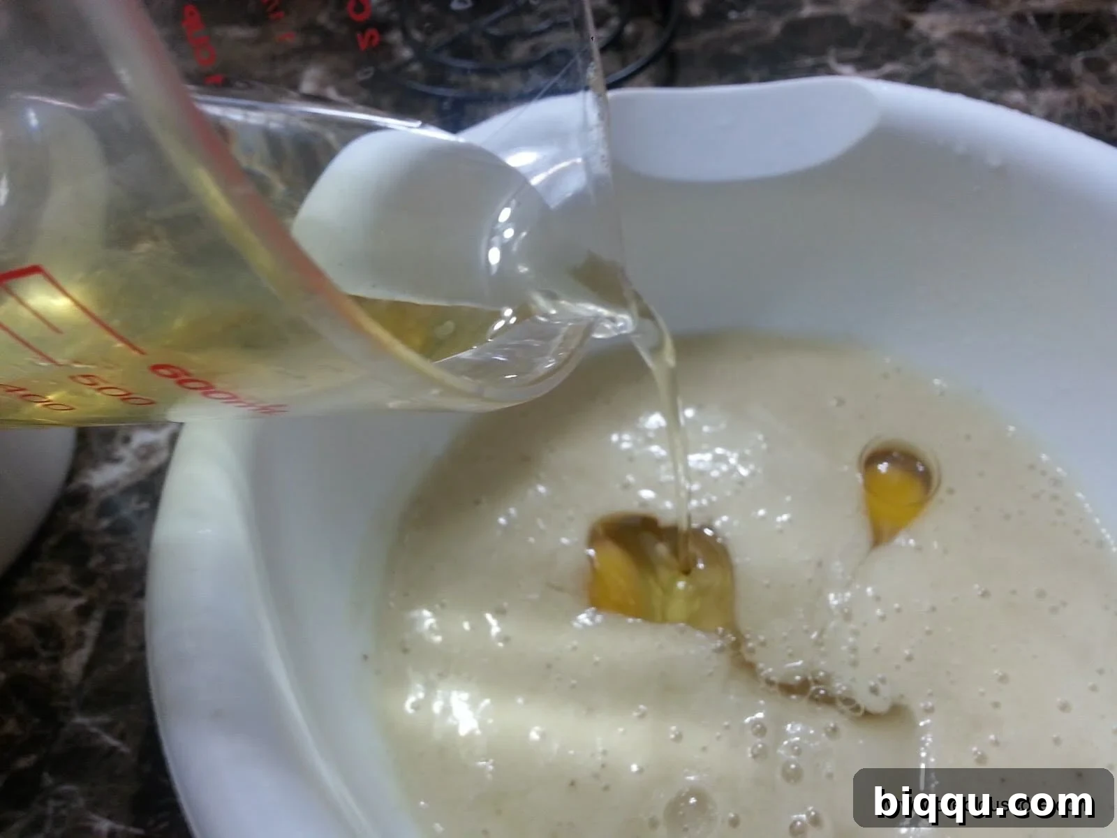 Vegetable oil pouring into a mixing bowl.