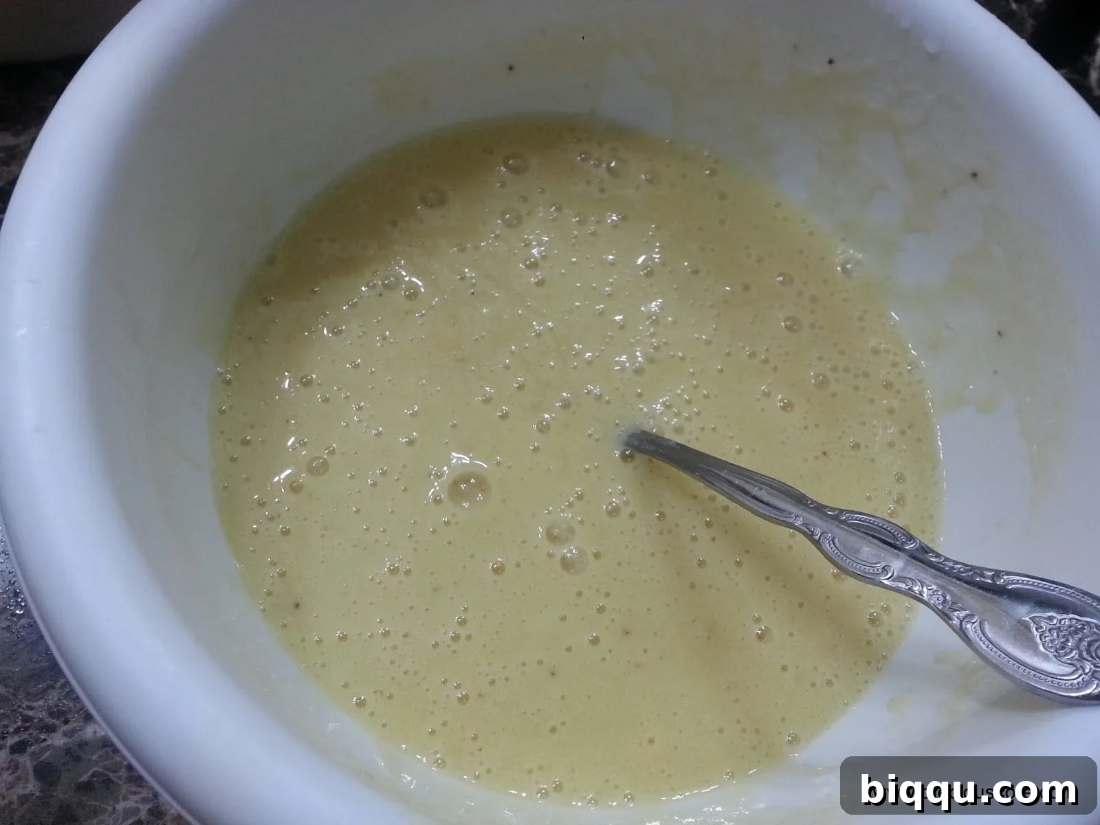 Spoon in a mixing bowl of wet ingredients.