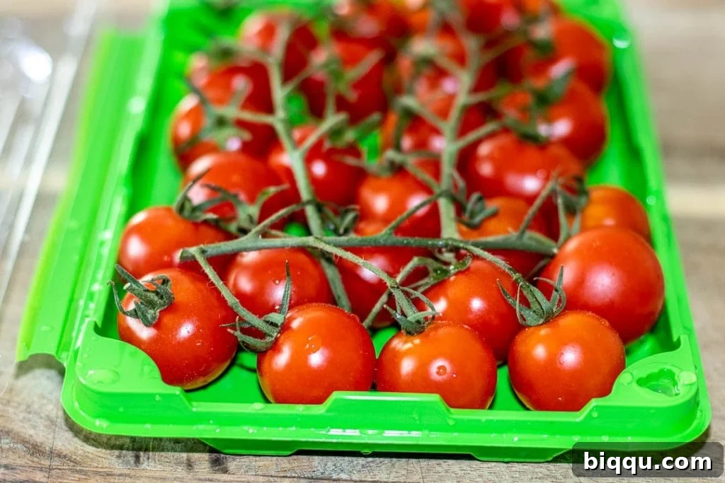 Fresh cherry tomatoes still on the vine, showcasing their vibrant red color and natural beauty.