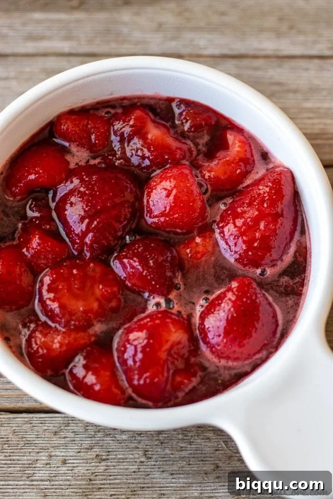 A glass bowl filled with a rich, ruby-red homemade strawberry sauce, perfect for topping pancakes or waffles.