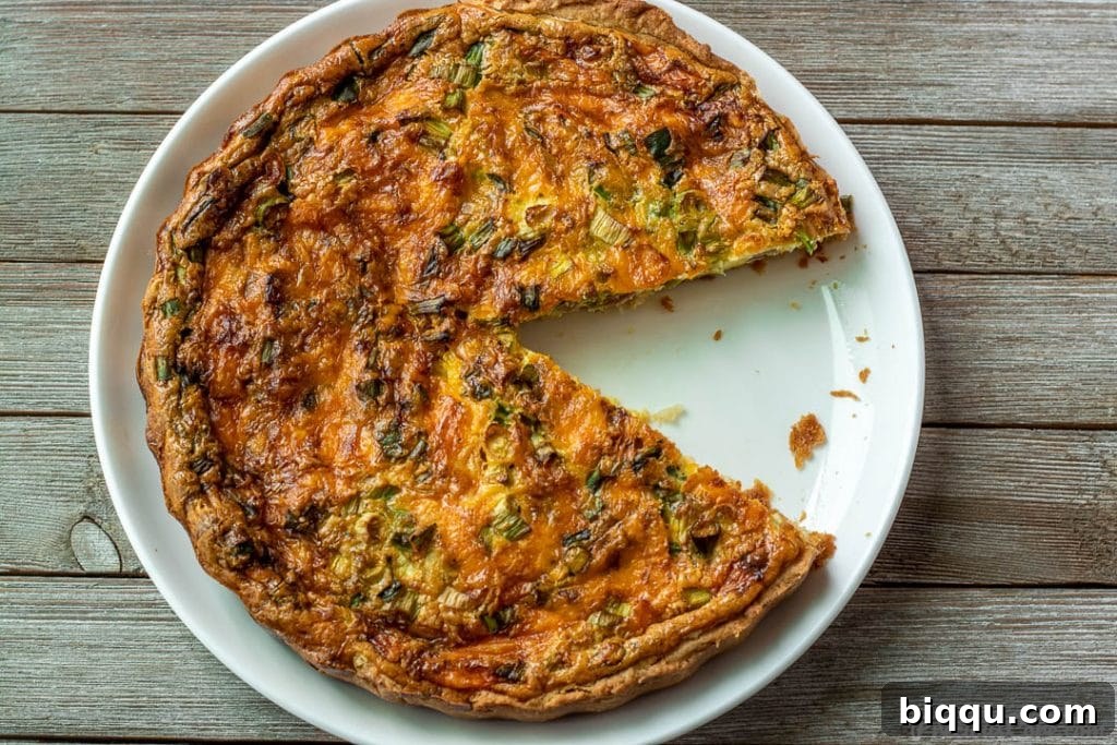 Deliciously Simple Quiche 4 A baked Quiche with a perfect slice cut out, ready to be served, revealing its rich, layered filling.