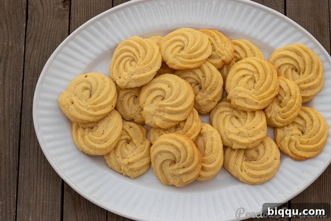 A landscape shot of golden Danish Butter Cookies cooling on a wire rack, showcasing their intricate piped designs.