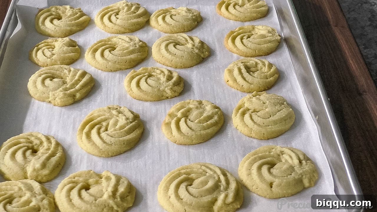 Freshly baked Danish Butter Cookies, still warm on the baking sheet, with a perfect golden hue.
