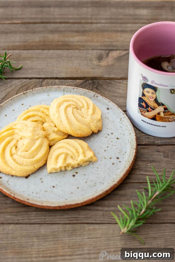 Danish Butter Cookies served on a saucer alongside a cup of hot tea, inviting a cozy break.