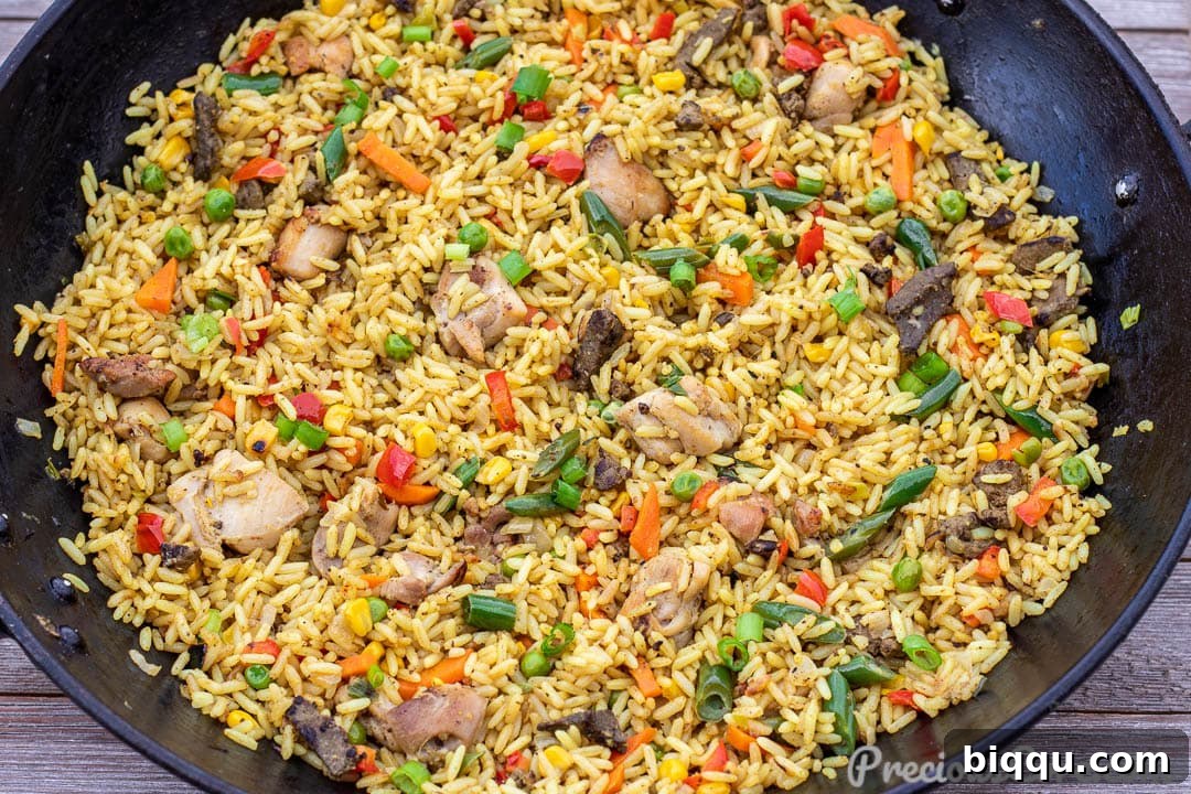 A wok filled with African Fried Rice, featuring chicken and liver pieces