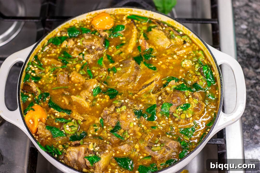 A large pot of simmering African Okra Soup, rich with ingredients and vibrant colors, ready to be served.