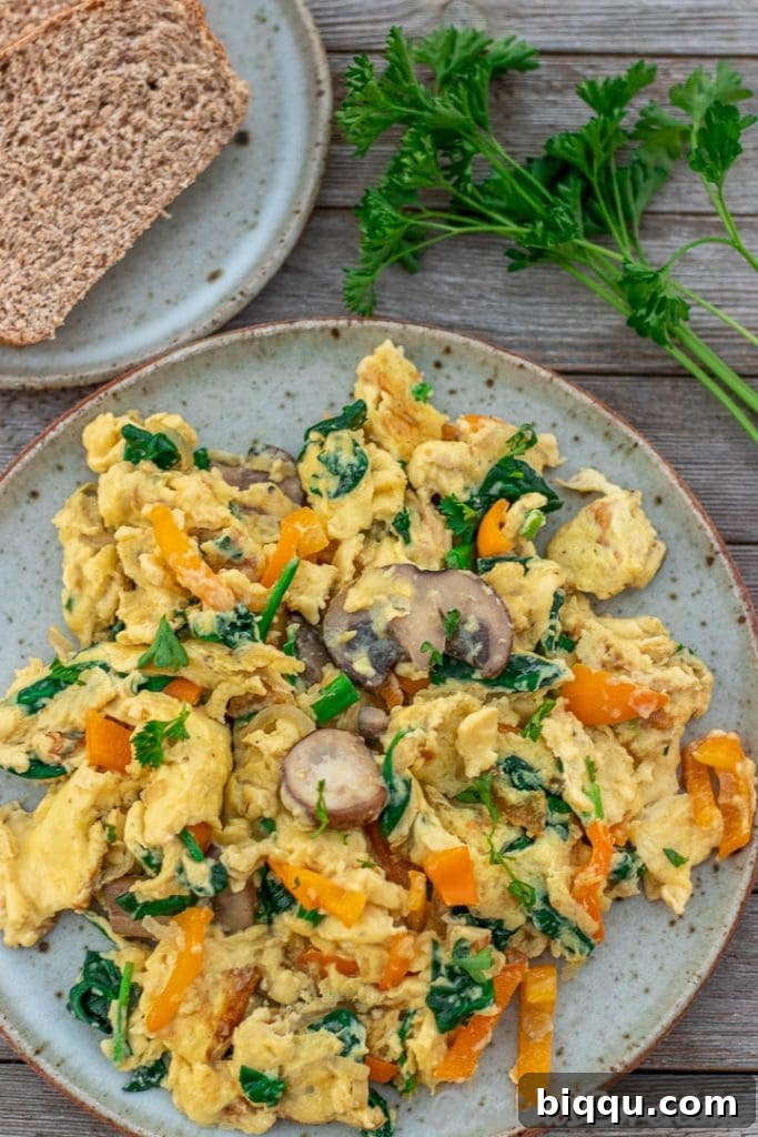 Scrambled Eggs with Vegetables on a plate with honey whole wheat toast on the side