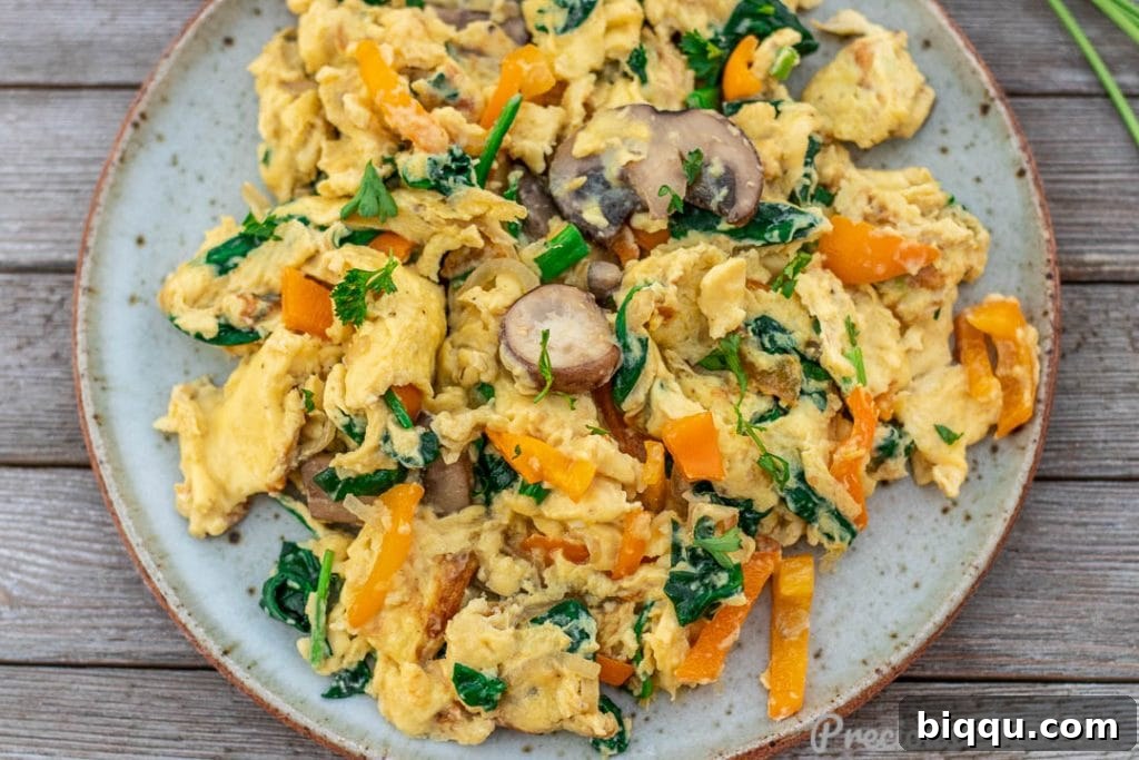 Landscape picture of creamy scrambled eggs with vegetables in a non-stick pan
