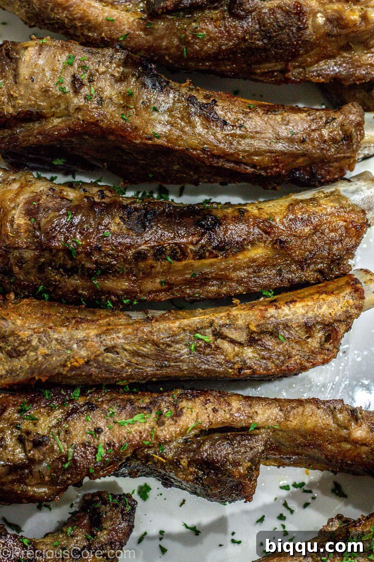 Crispy, broiled ribs arranged invitingly on a white serving platter, ready to be enjoyed.