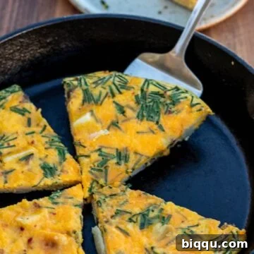 Golden-brown slices of Potato Frittata nestled in a rustic cast iron skillet, ready to be served.
