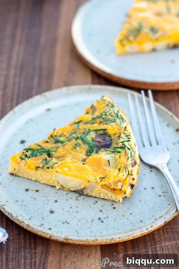 A perfectly cooked slice of Potato Frittata resting on a pristine white plate, showcasing its golden crust and fluffy interior.