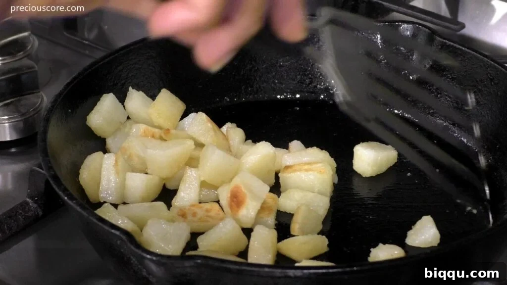 A close-up view of perfectly cooked diced potatoes, golden and slightly crispy, resting in a skillet.