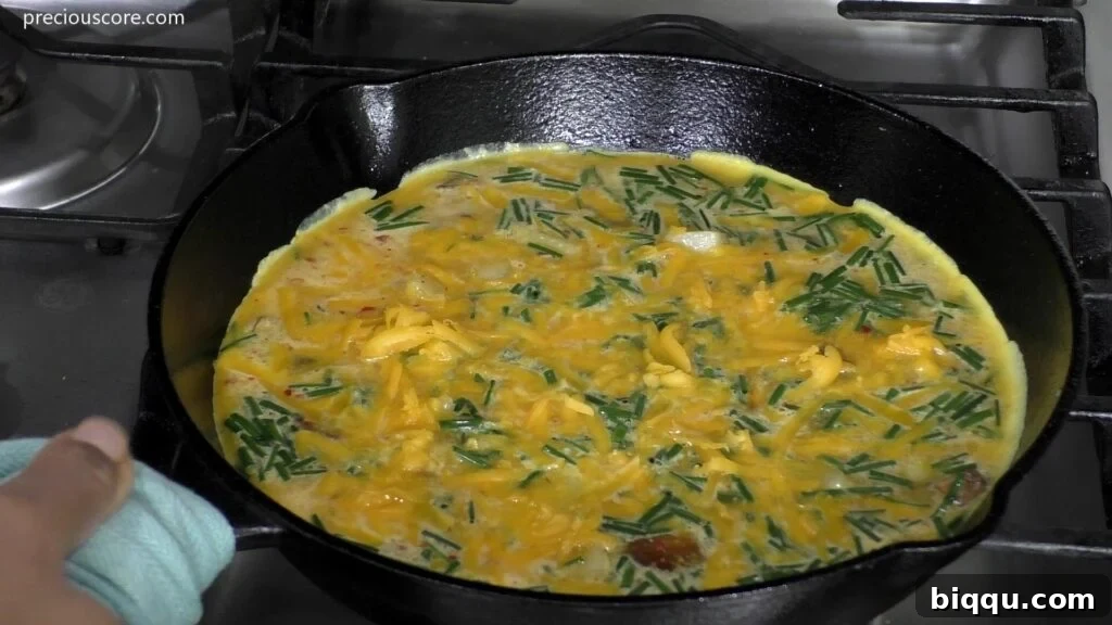 The Potato Frittata mixture, with eggs, potatoes, and mushrooms, cooking and bubbling gently in a skillet on the stovetop.