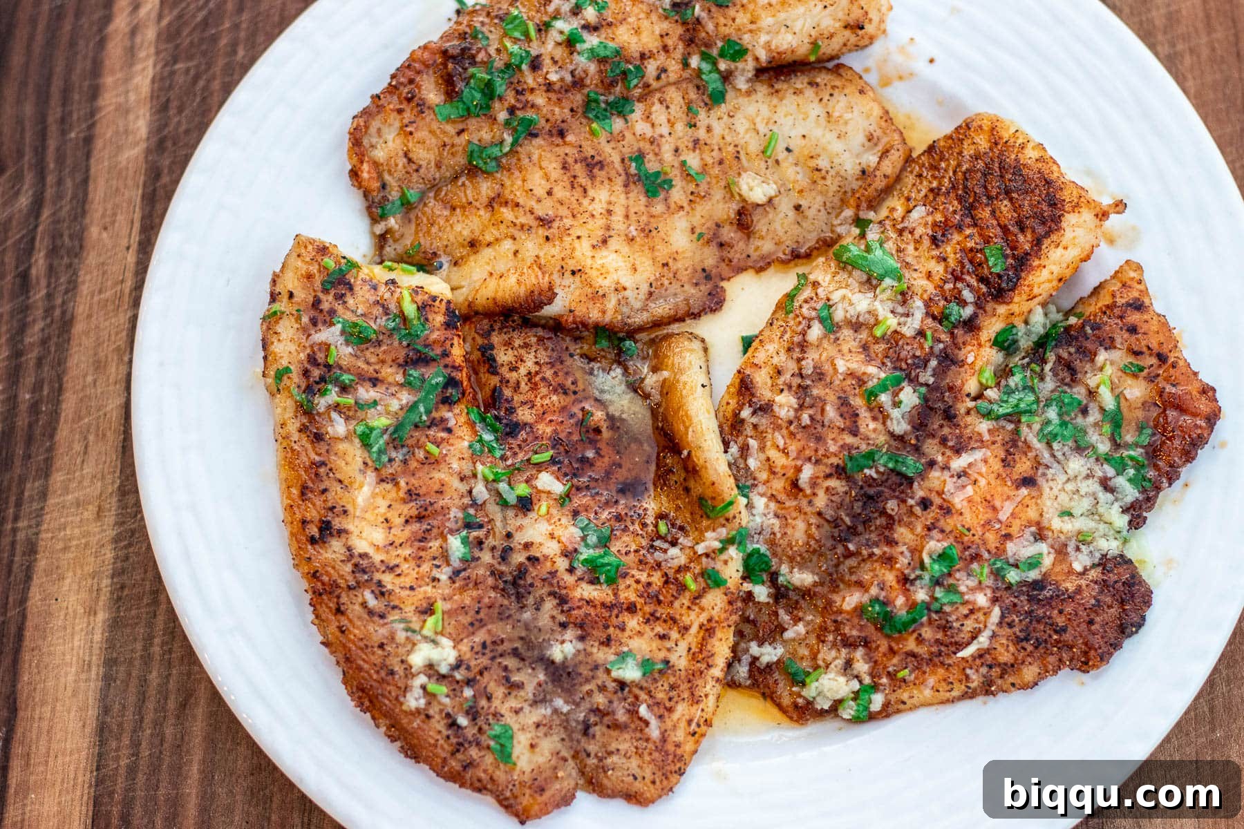 Landscape photo of cooked lemon butter tilapia with a luscious sauce and fresh herbs, ready to be served.