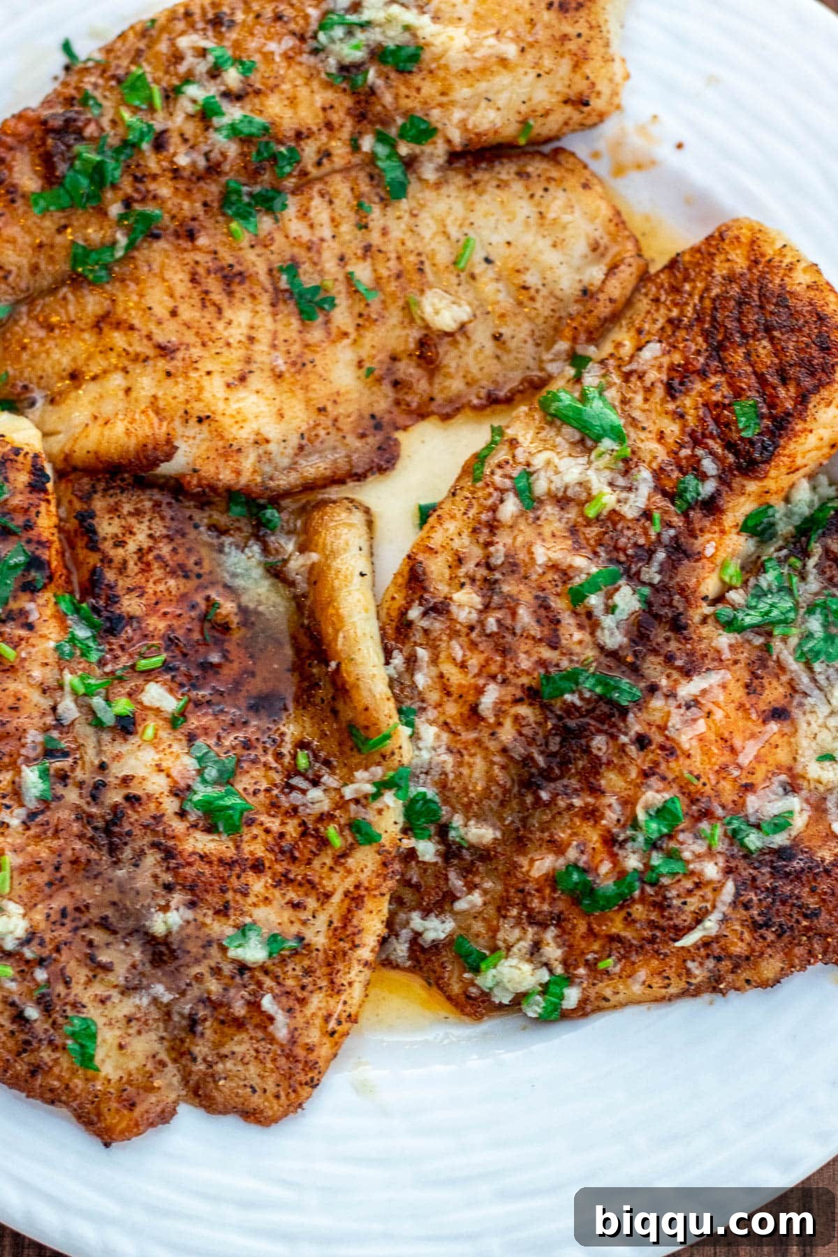 Cooked tilapia fillets in lemon butter sauce, exquisitely plated and ready for enjoyment.