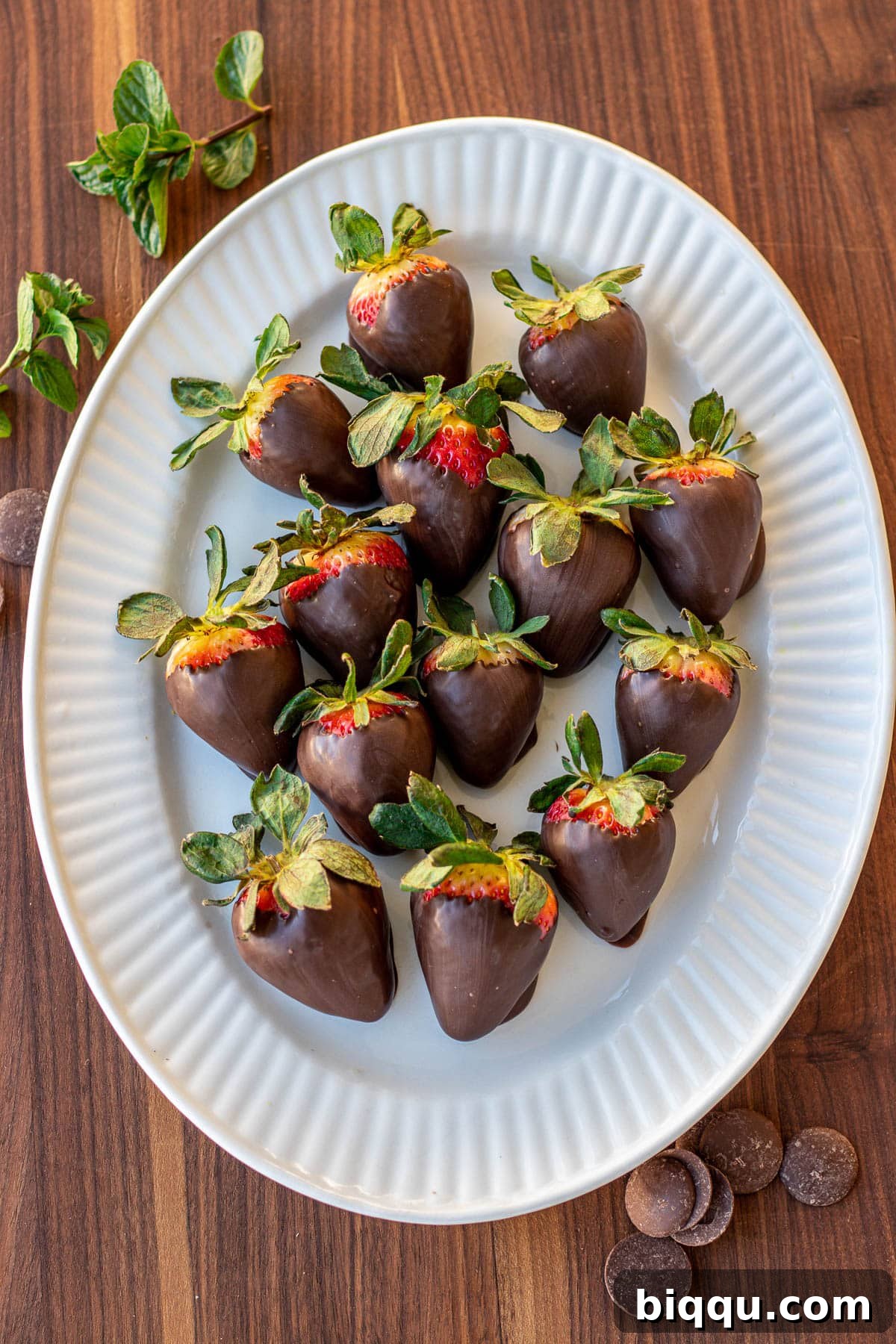 A stunning close-up of strawberries lavishly covered in rich, dark chocolate, meticulously arranged on an elegant serving platter, ready to be devoured.
