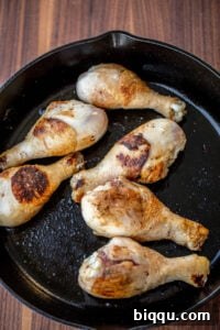 Browned chicken drumsticks ready for the creamy sauce in a cast iron skillet.