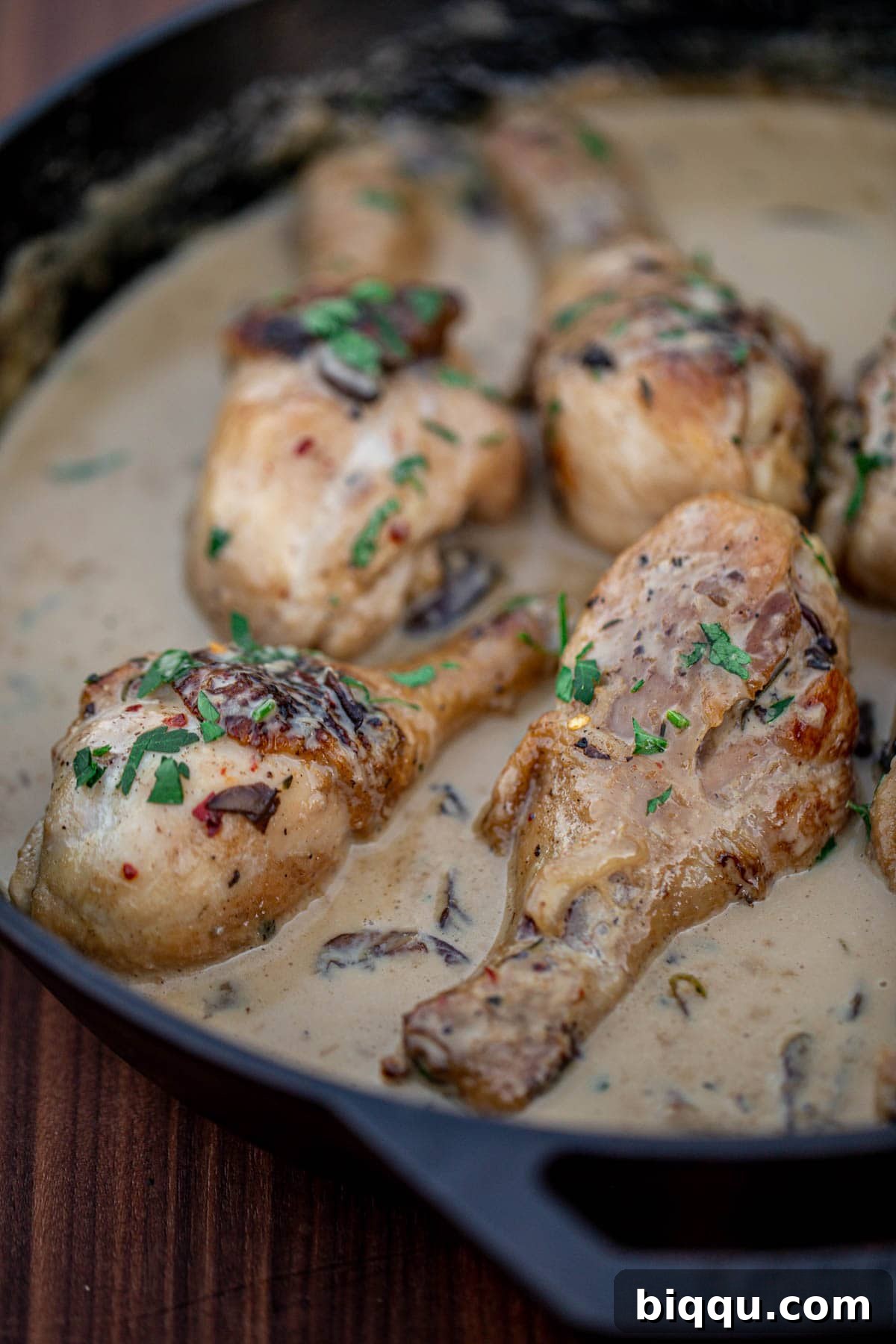 Creamy chicken drumsticks served fresh from the skillet, beautifully garnished with vibrant fresh herbs, ready to be enjoyed.