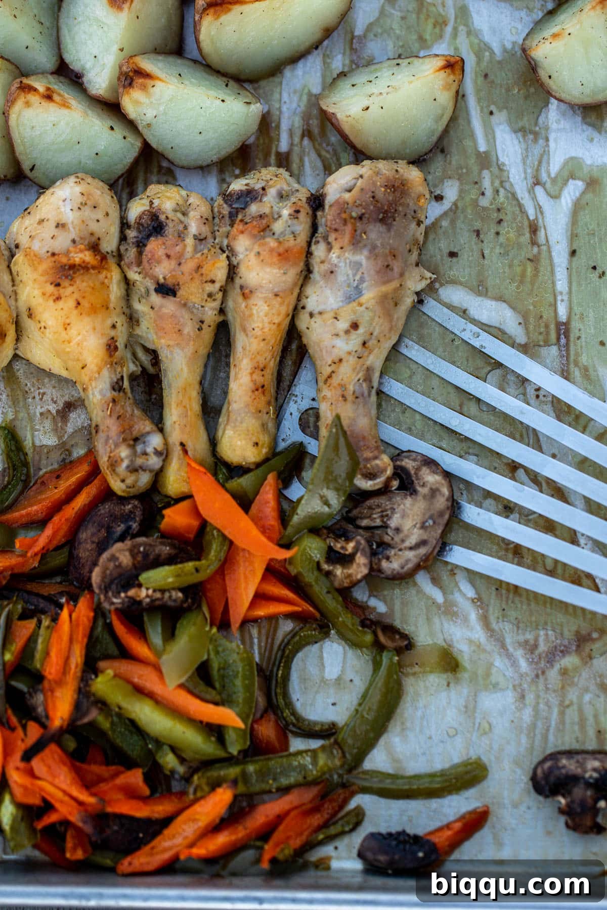 One pan chicken and potatoes and veggies being dished onto a plate with a fish spatula