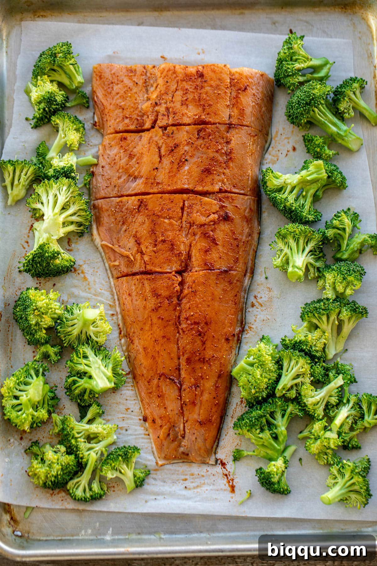 Seasoned salmon and broccoli arranged on a sheet pan, ready to go into the oven