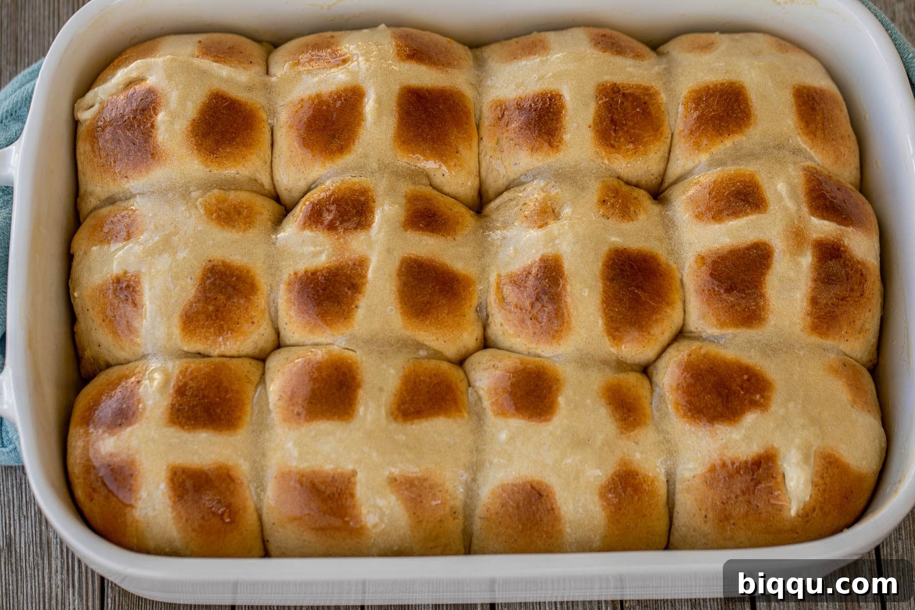 A landscape view of a tray of freshly baked Hot Cross Buns, beautifully arranged and ready to be served, highlighting their golden color and intricate crosses.