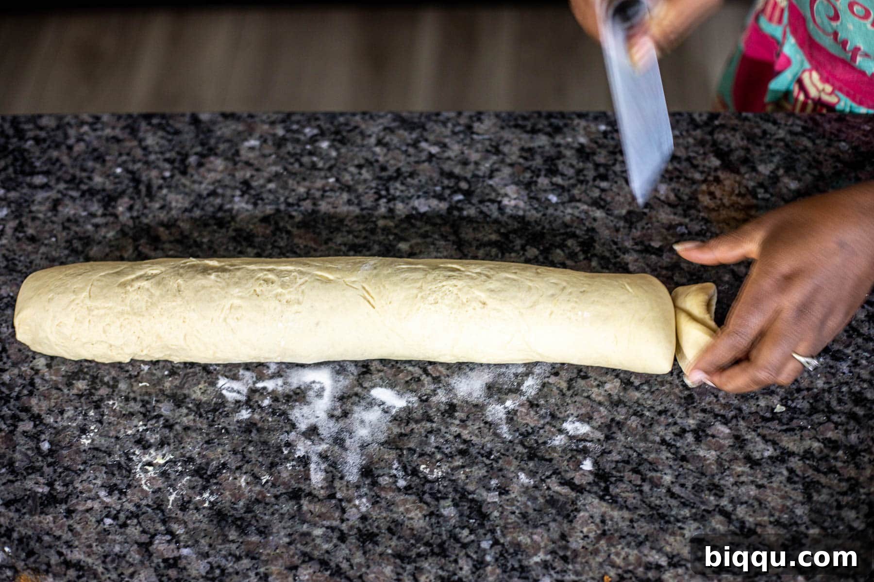Hand trimming ends of cinnamon rolls log.