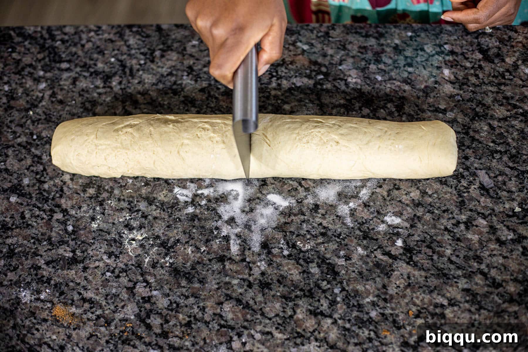Cutting dough in the middle using a dough scraper.