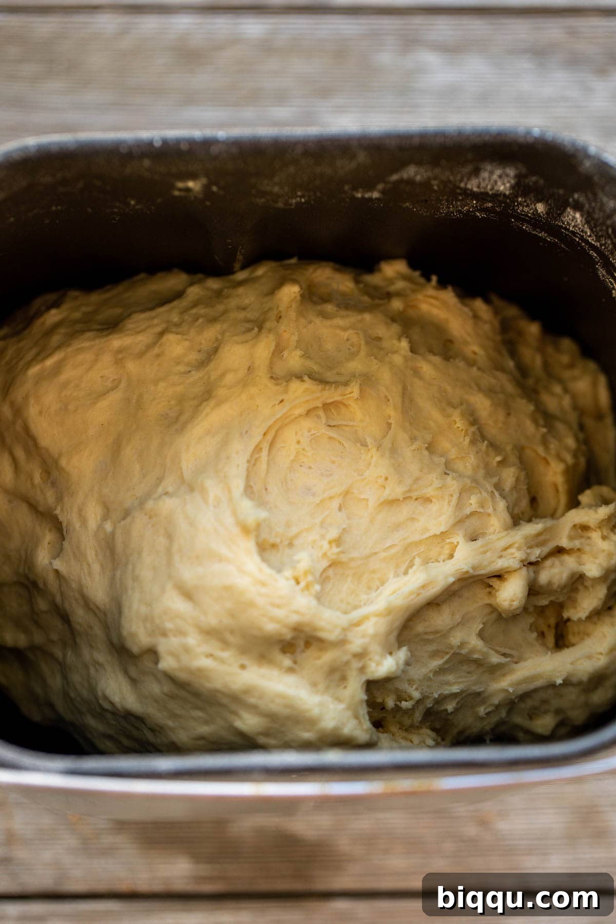 Cinnamon rolls dough in the bowl of a bread machine.