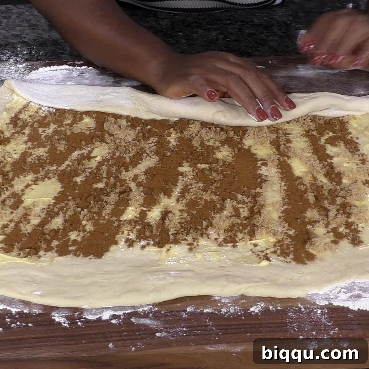Hand rolling cinnamon roll dough into a log.
