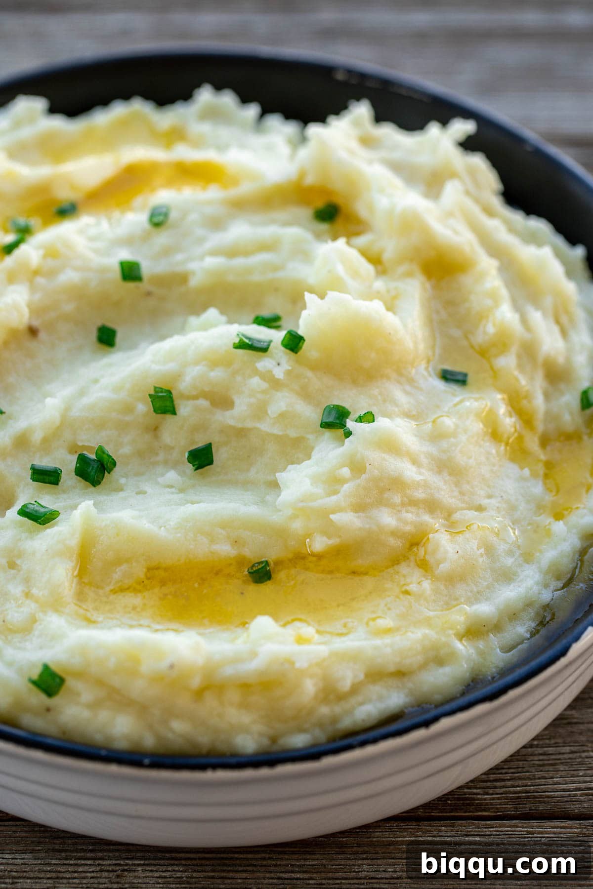 A beautifully presented bowl of creamy buttermilk mashed potatoes, garnished with fresh herbs.