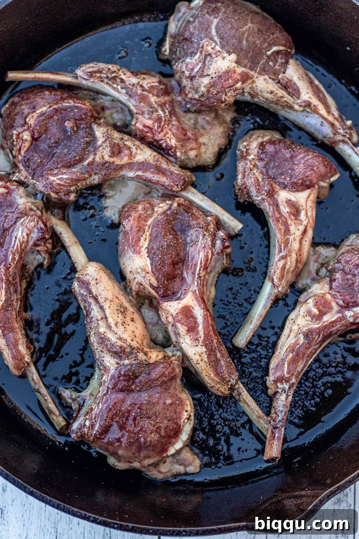 Lamb chops sizzling in a hot cast iron skillet, creating a perfect sear.