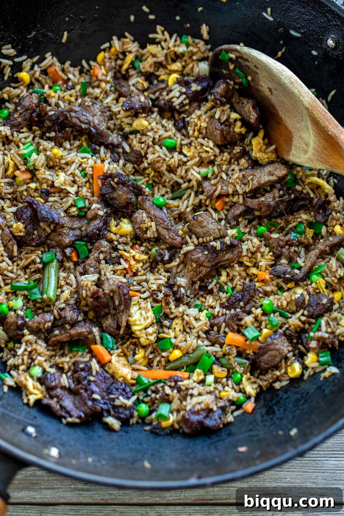 A black wok filled with freshly prepared steak fried rice, showing the vibrant mix of ingredients.