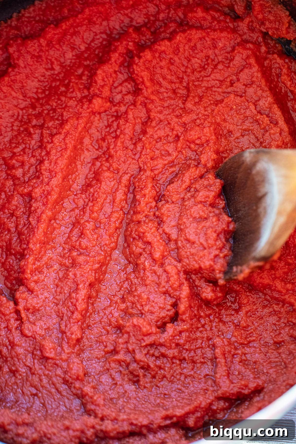 Thickening tomato puree simmering in a large pot on the stove