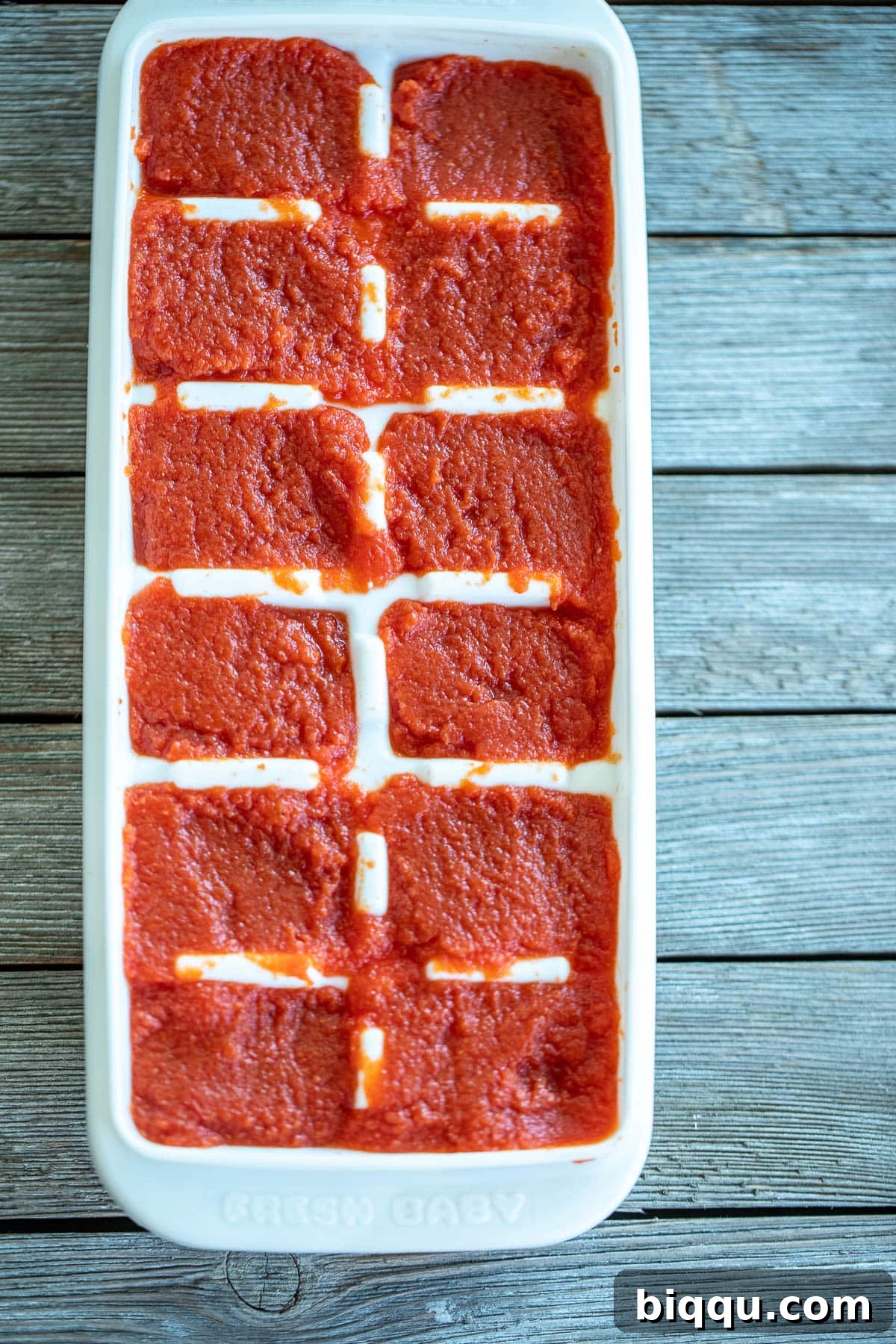Homemade tomato paste neatly portioned in an ice cube tray, ready for freezing.