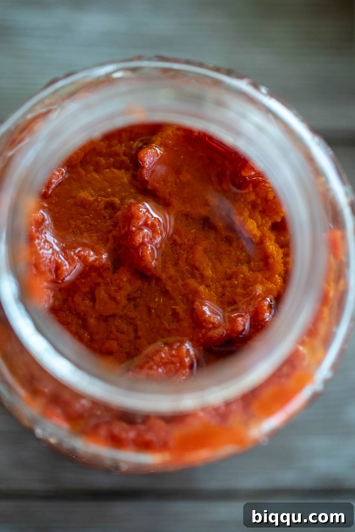 Homemade tomato paste stored in a mason jar, topped with a layer of olive oil.