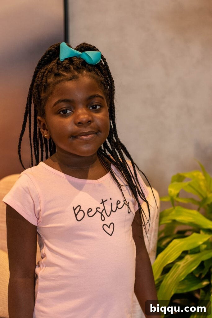 A young girl in a vibrant pink t-shirt looking curious and engaged.