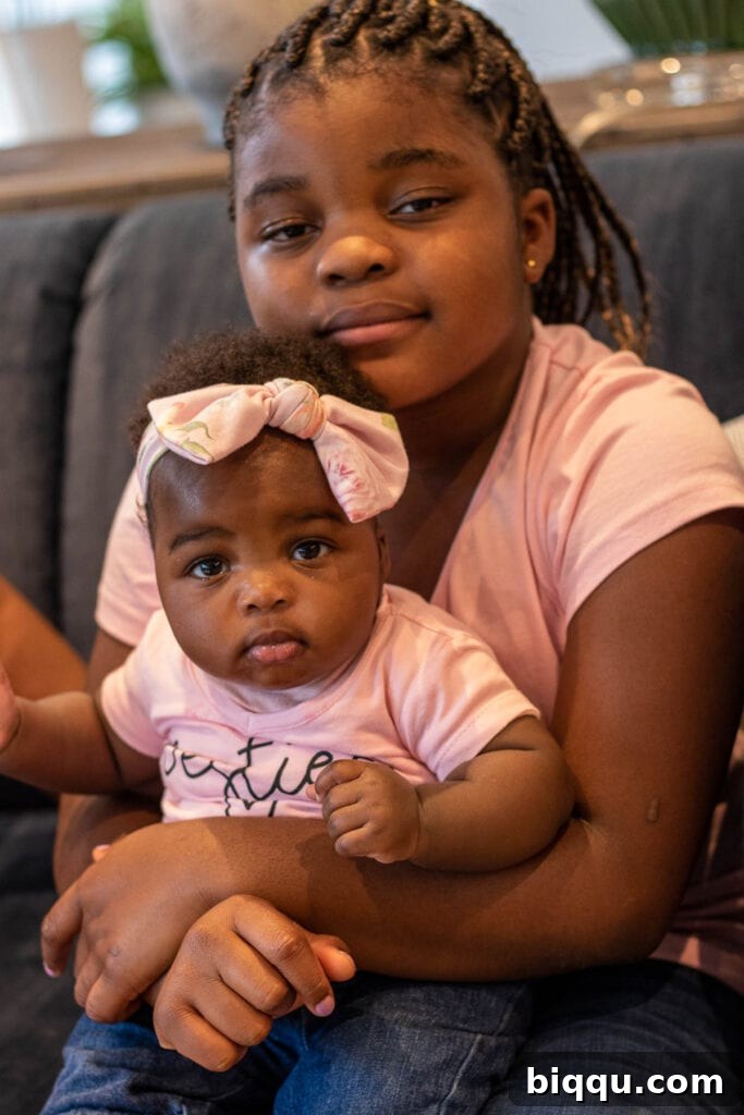 An older sister lovingly carrying her younger sister, a sweet moment of sibling bonding.
